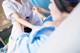 A woman in a hospital bed being examined by a nurse.