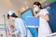 A woman in a white lab coat and a nurse in a blue uniform.