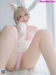 A woman in a bunny costume is sitting on a bed.