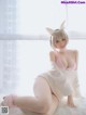 A woman in a bunny costume sitting on a bed.