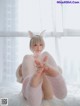 A woman in a bunny costume sitting on a white rug.