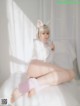 A woman in a white bunny costume sitting on a bed.