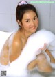 A young woman sitting in a bathtub covered in foam.