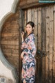 A woman in a kimono leaning against a wooden door.