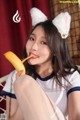 A woman in a cat ears outfit eating a banana.