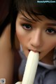 A young woman eating a banana with her mouth open.