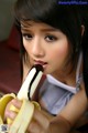 A young woman eating a banana with chocolate on it.