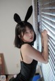 A woman in a black dress with bunny ears on her head.