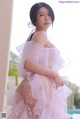 A woman in a pink dress posing by a pool.