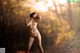 A nude woman standing in the middle of a forest.