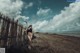 A woman standing on a beach next to a fence.