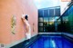 A naked woman leaning against a wall next to a swimming pool.