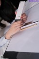 A woman holding a pen and writing on a piece of paper.