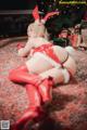 A woman in a red and white outfit laying on a rug.