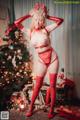 A woman in a red lingerie posing in front of a Christmas tree.