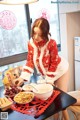 A woman in a red and white dress preparing food on a table.