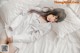 A woman laying on top of a bed in a white shirt.