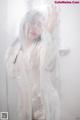 A woman in a white robe standing in front of a shower.