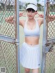 A woman in a white tennis outfit posing for a picture.