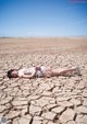 A woman laying on the ground in the middle of a desert.