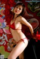 A woman in a red bikini posing in front of a graffiti wall.