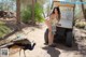 A woman kneeling down next to a golf cart with a peacock.