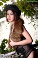 A woman in a black hat and fur vest posing for a picture.