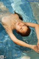 A woman floating in a swimming pool with her arms outstretched.