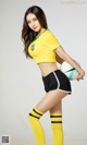 A woman in a yellow shirt and black shorts holding a soccer ball.