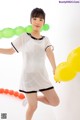 A woman in a white shirt and black shorts holding a bunch of balloons.