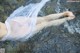 A woman in a white dress laying in the water.