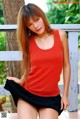 A woman in a red tank top and black skirt posing for a picture.