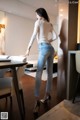 A woman in a white shirt and jeans standing in a room.