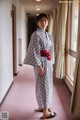 A woman in a black and white kimono standing in a hallway.