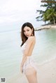 A woman in a white dress standing on a beach.