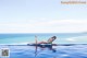 A woman in a blue bikini laying on the edge of a swimming pool.