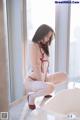 A woman in a white lingerie sitting on a bathtub.