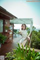 A woman in a white dress standing on a wooden deck.