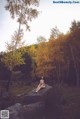 A woman sitting on a rock in the middle of a forest.