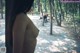 A woman standing in a park next to a bench.