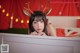 A woman wearing reindeer antlers on her head in front of a red curtain.