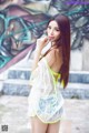 A woman in a white dress posing in front of a graffiti wall.