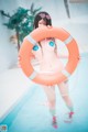 A woman in a bikini holding a life preserver in a pool.