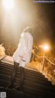 A woman in a white jacket and black stockings is walking up some stairs.