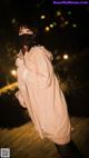 A woman wearing a face mask standing on a boardwalk at night.