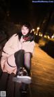 A woman sitting on a wooden bench at night.