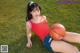 A woman in a red shirt and blue shorts holding a basketball.