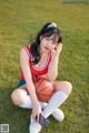 A woman sitting on the grass holding a basketball.