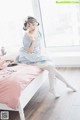 A woman sitting on a bed holding a lollipop.