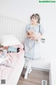 A woman standing on a bed holding a stuffed animal.